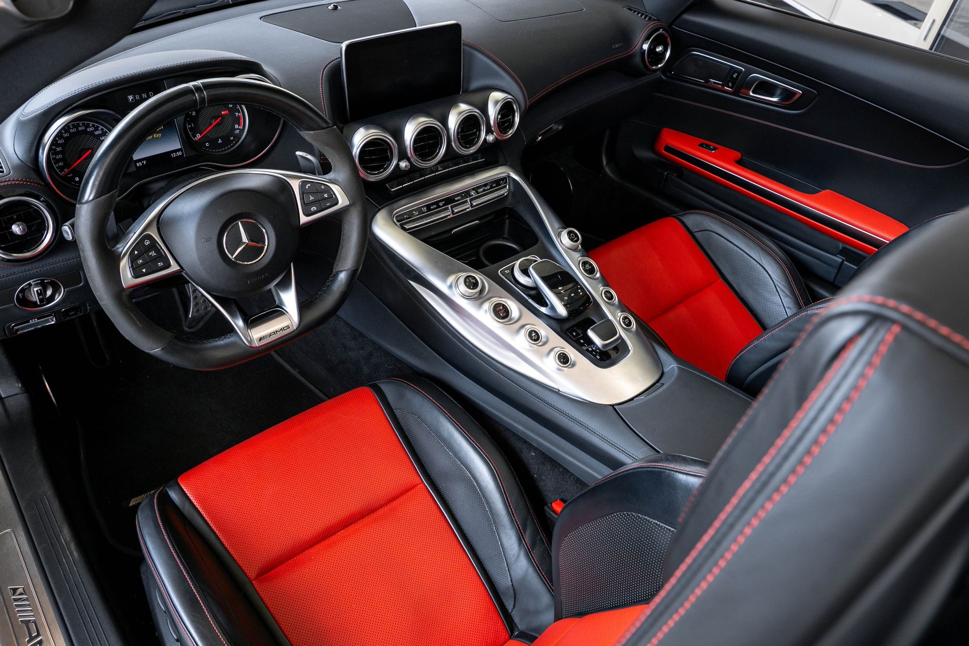 Mercedes-Benz car interior with black and red leather seats, silver accents, steering wheel, dashboard.