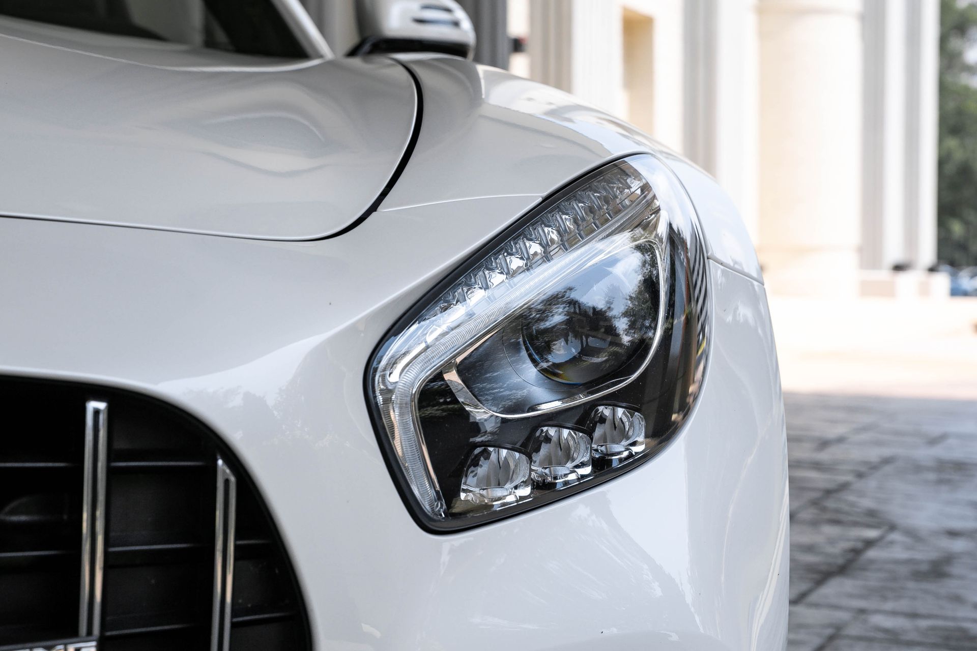 White sports car, close-up of front headlight.