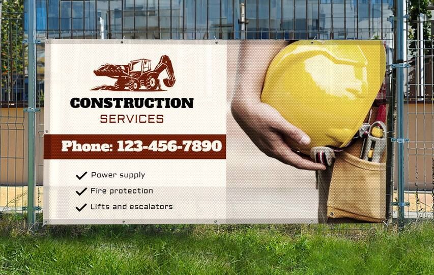 A banner for construction services is hanging on a fence