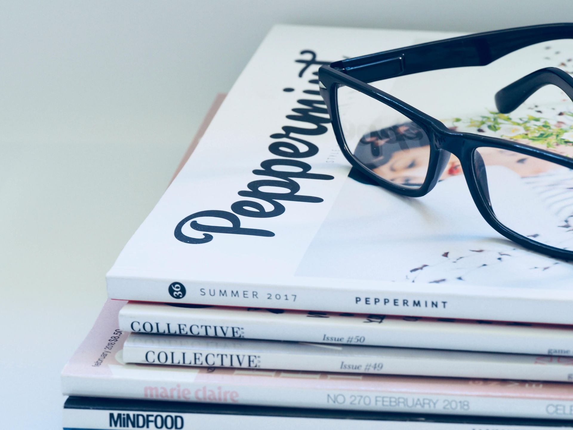 A pair of glasses sitting on top of a stack of peppermint magazines