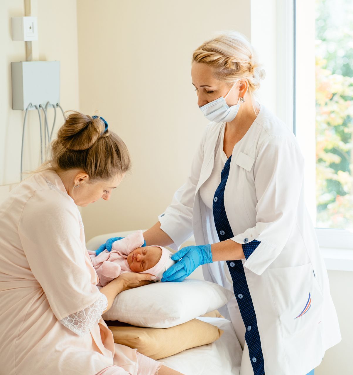 A woman is holding a baby while another woman looks on