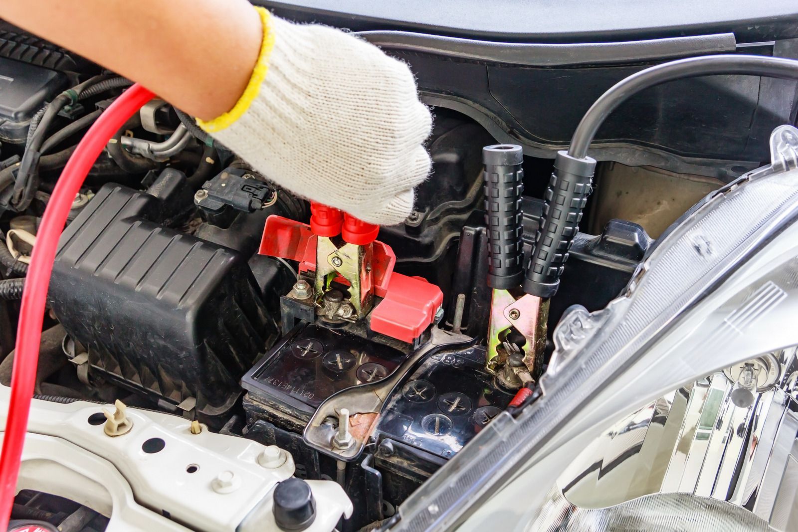 A person is charging a car battery with a jump starter.