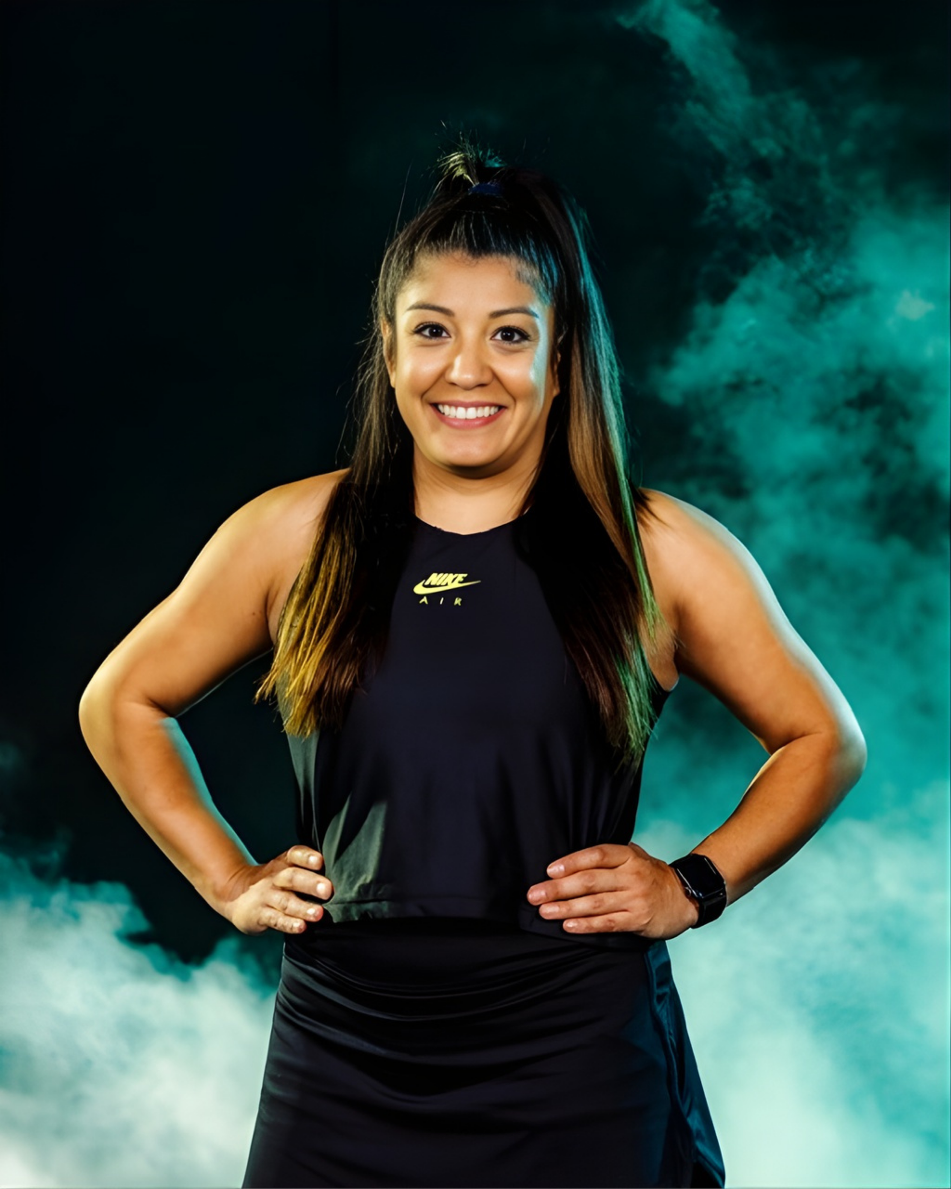 A smiling athlete in a black tank top and skirt stands with hands on hips against a backdrop of swirling teal smoke.