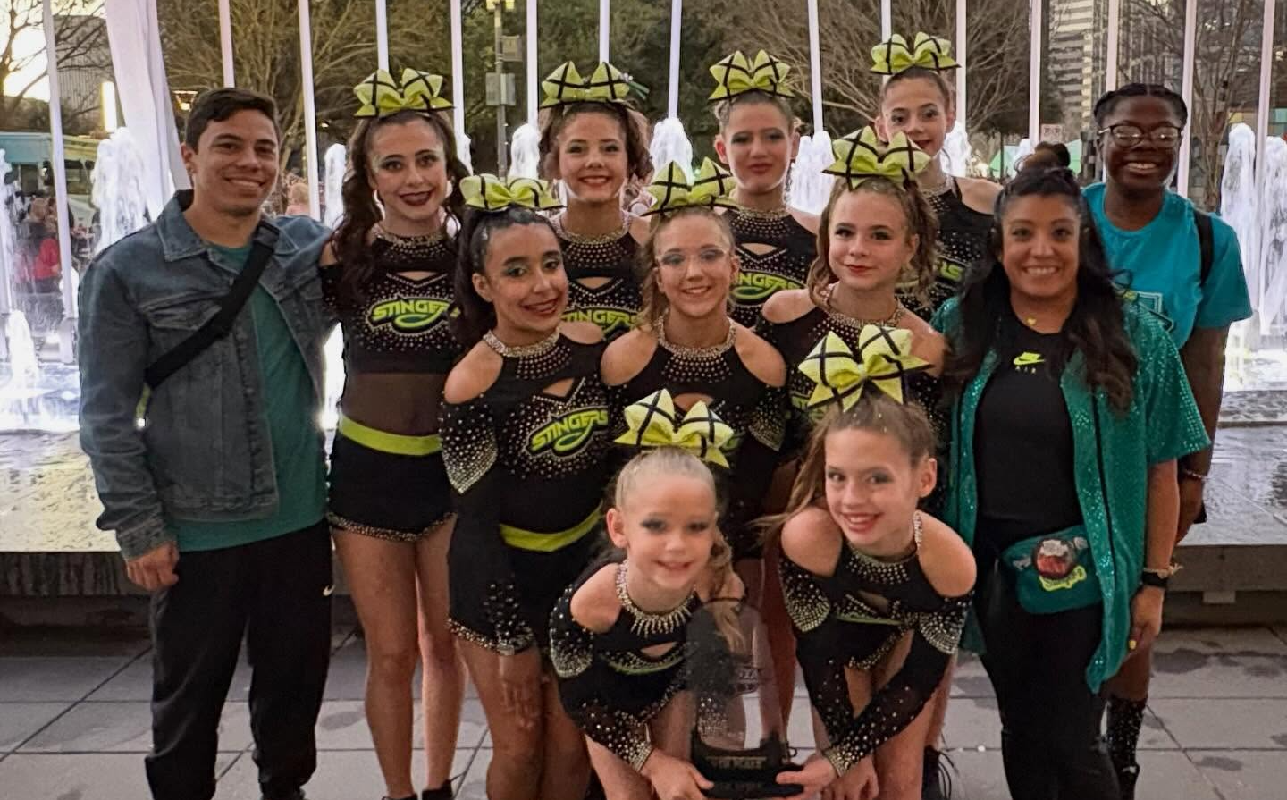 Children in cheerleading uniforms smile with arms around each other.