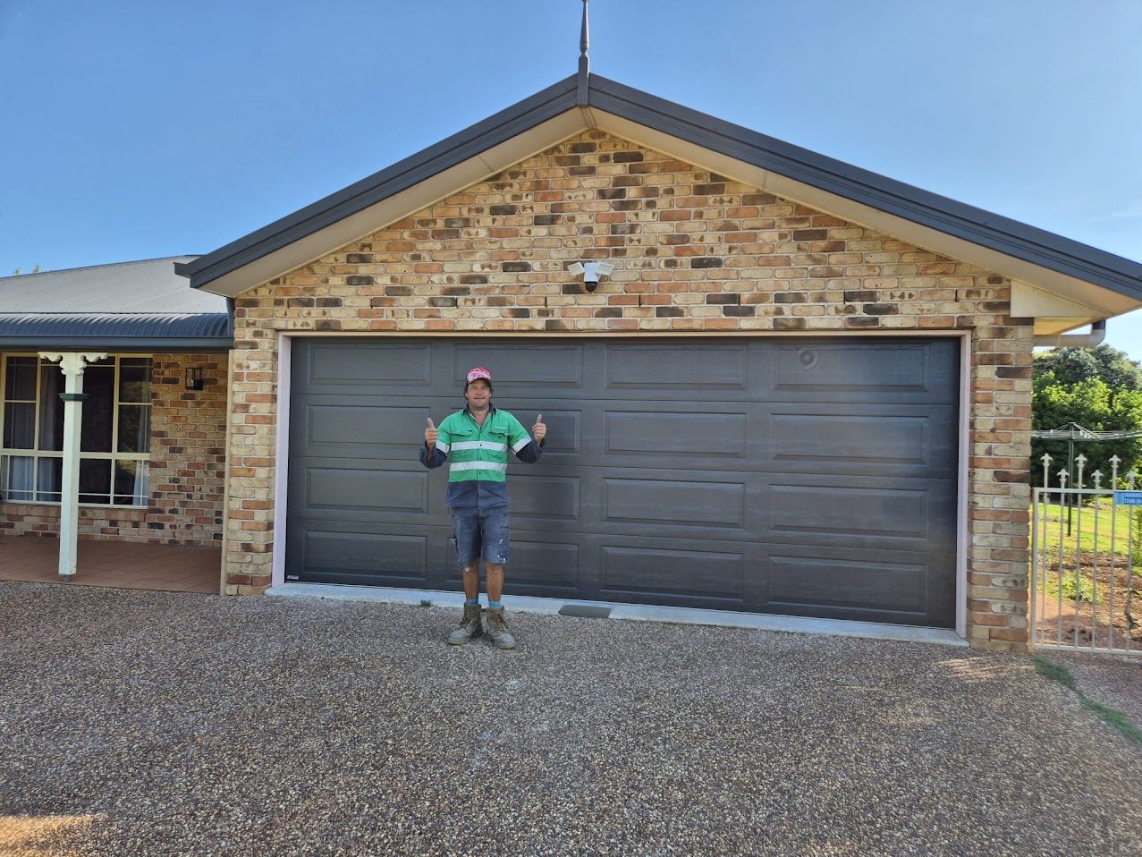 Workers near a van with open doors, tools visible. They are by a trailer with a patio under construction. Sunny, outdoor.
