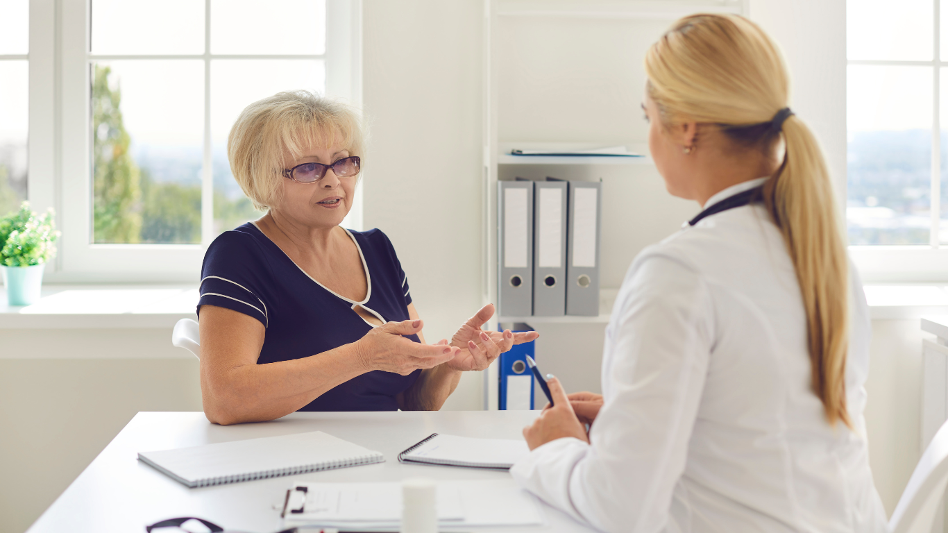 A woman is sitting at a table talking to a doctor.
