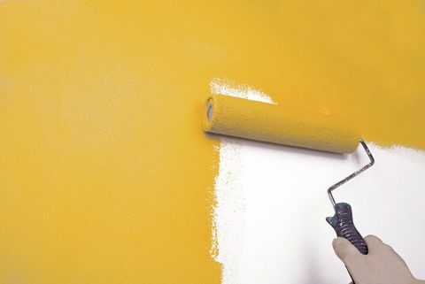 paint roller painting a wall yellow