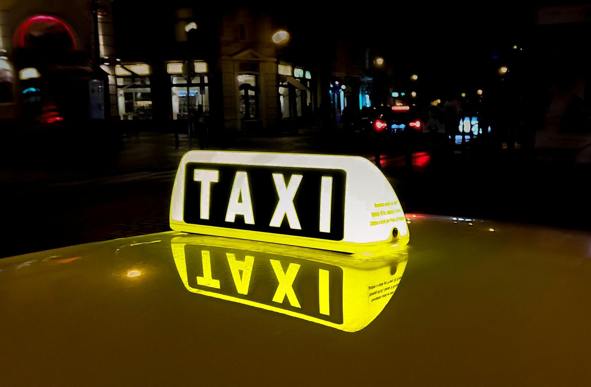 A taxi sign on top of a car at night