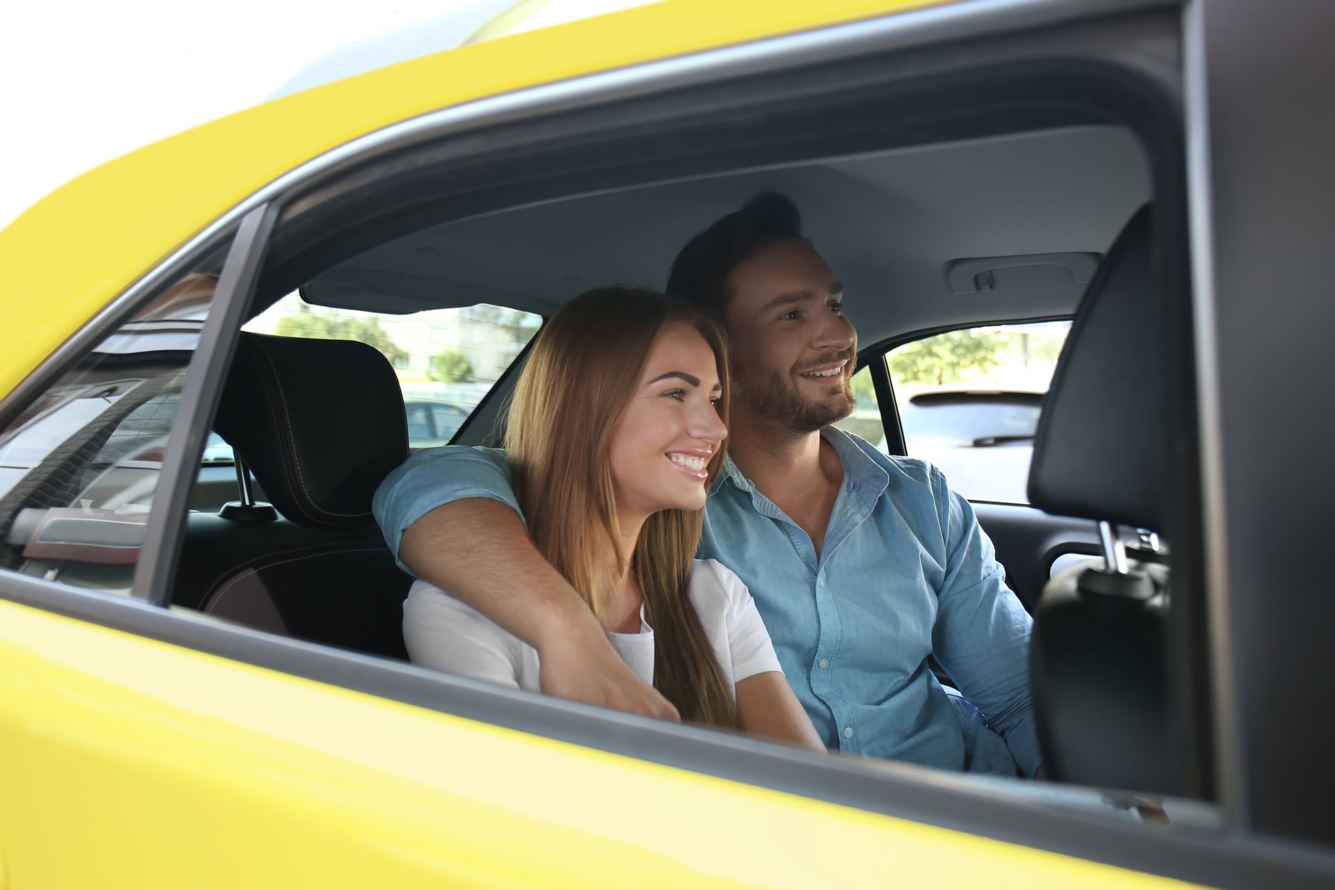 A man and a woman are sitting in a yellow car looking out the window.