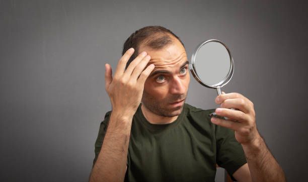 A man looking at the mirror at Drs. Berry, Luther & Aronovitz for hair restoration in Troy, MI