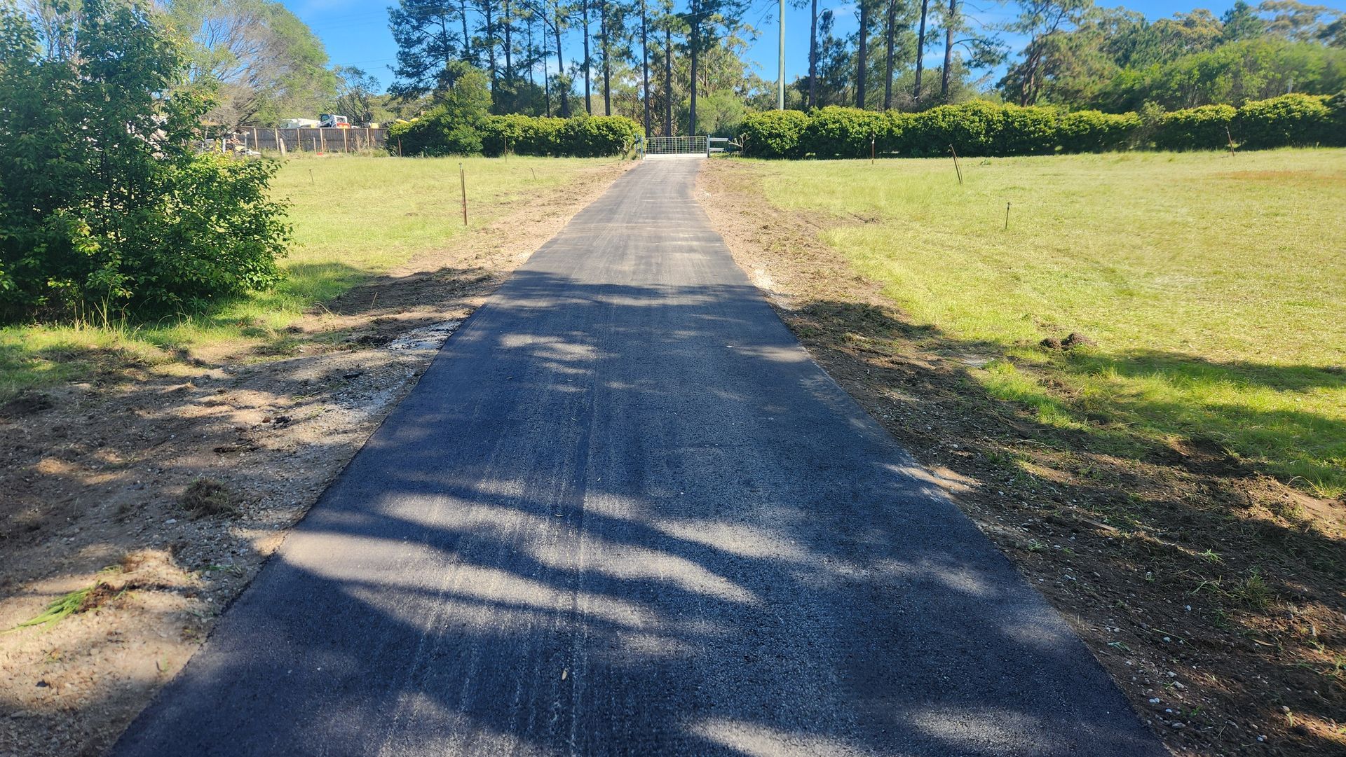 Asphalt Driveway Through Grassy Area, Trees In The Background — TAC Asphalt Services in Warners Bay, NSW