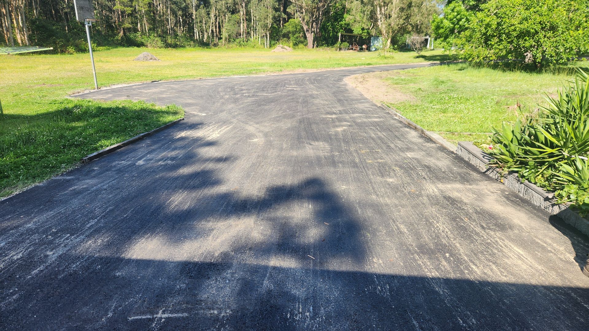 Asphalt Driveway Curves Through Grassy Area — TAC Asphalt Services in Warners Bay, NSW