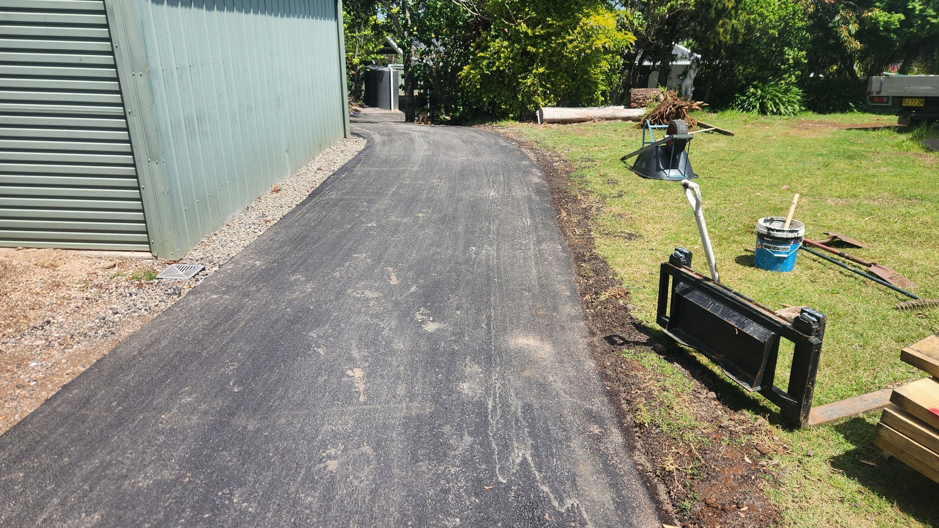 Asphalt Driveway Curves Past A Green Corrugated Metal Building — TAC Asphalt Services in Warners Bay, NSW