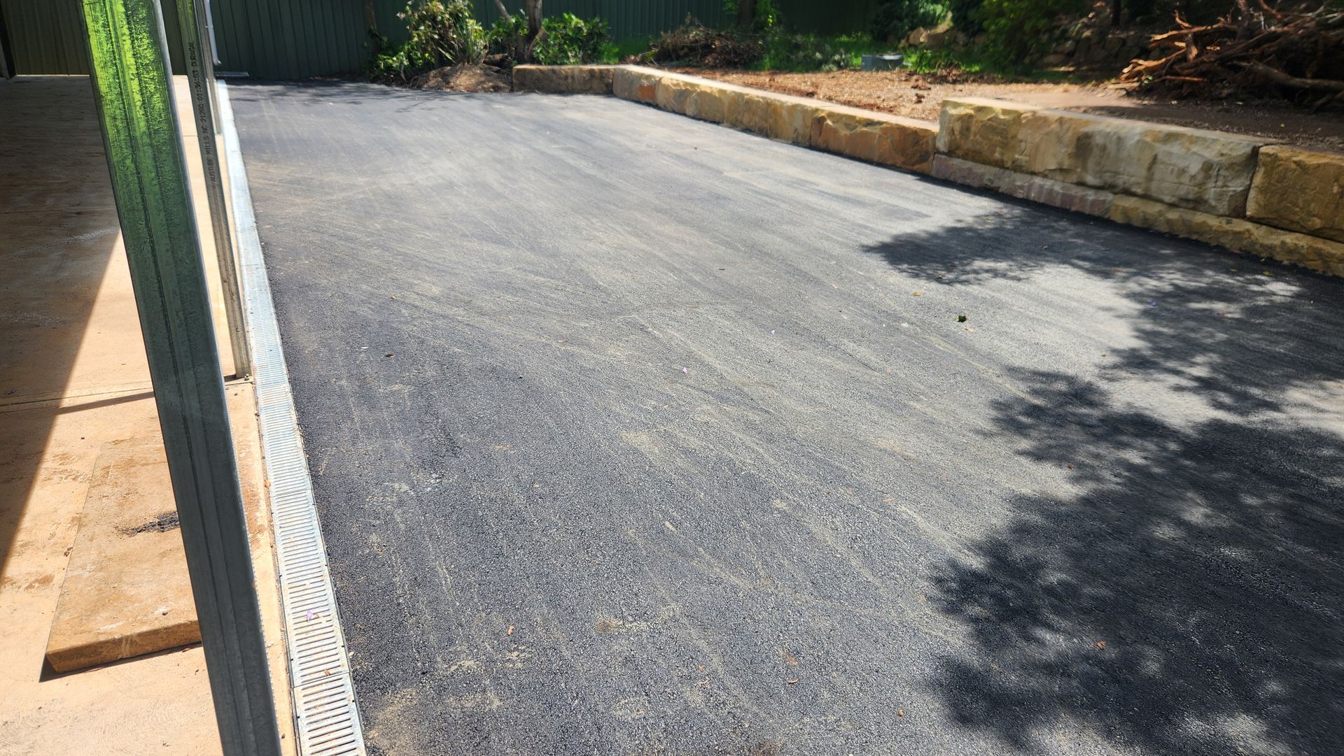 Gravel Driveway Beside A Retaining Wall. A Metal Frame Is On The Left — TAC Asphalt Services in Warners Bay, NSW