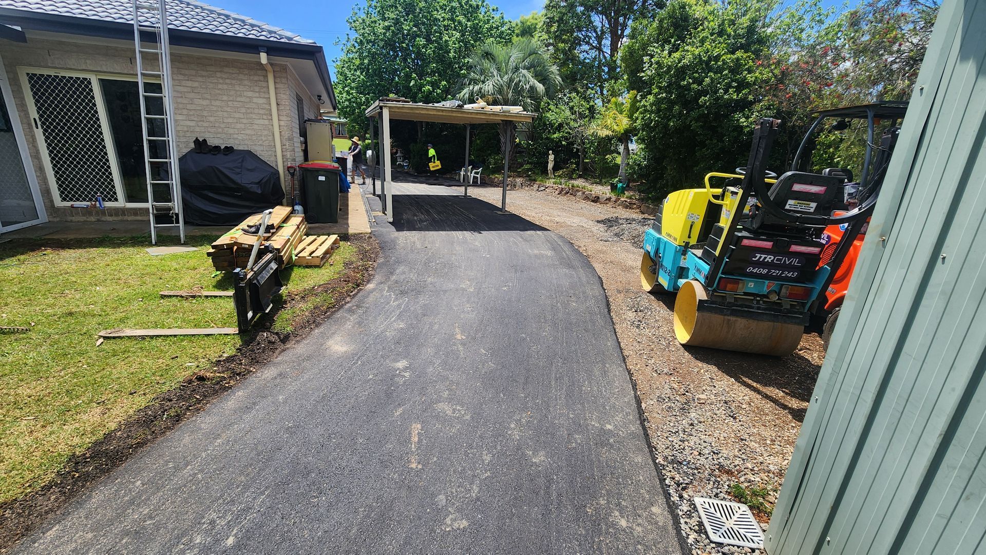 Asphalt Driveway With Construction Equipment And A Shed In A Residential Yard — TAC Asphalt Services in Warners Bay, NSW