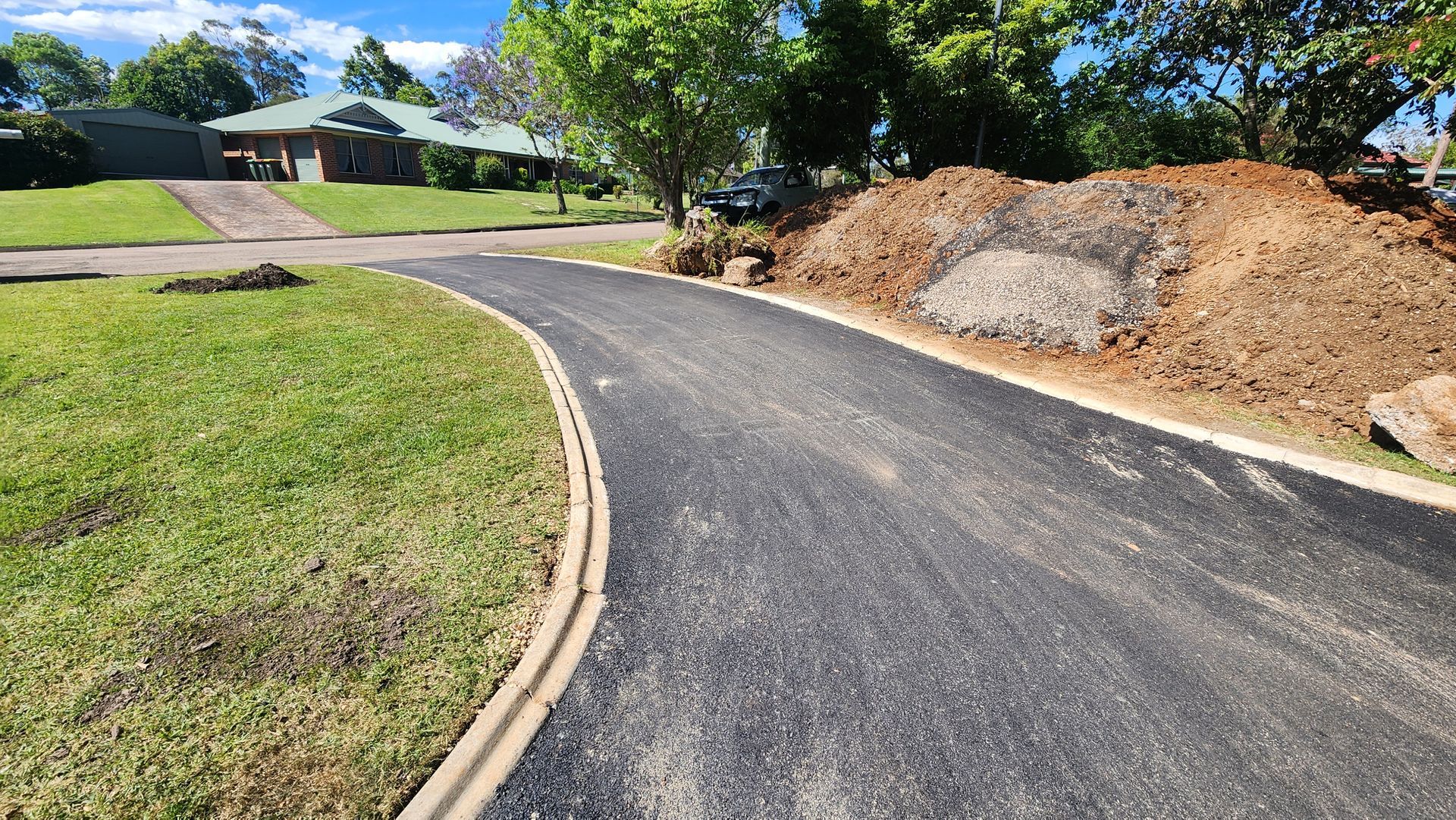 Newly Paved Asphalt Driveway With Dirt Pile — TAC Asphalt Services in Warners Bay, NSW