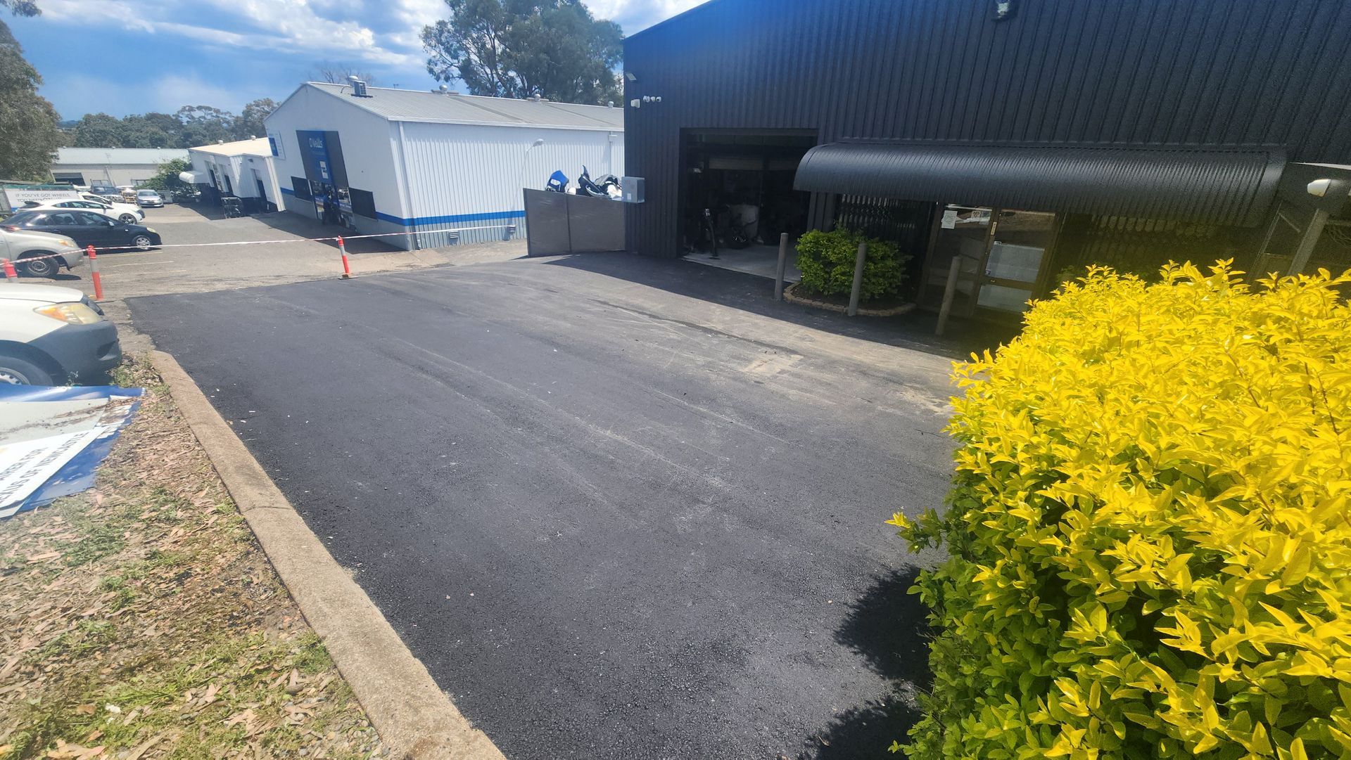 Newly Paved Asphalt Driveway Leading Toward a Dark Building — TAC Asphalt Services in Lake Macquarie, NSW