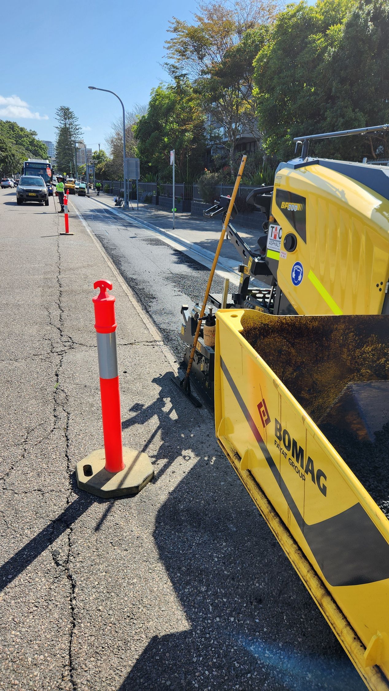 Road Resurfacing With a Yellow Paving Machine. Orange Cones for Traffic — TAC Asphalt Services in Lake Macquarie, NSW