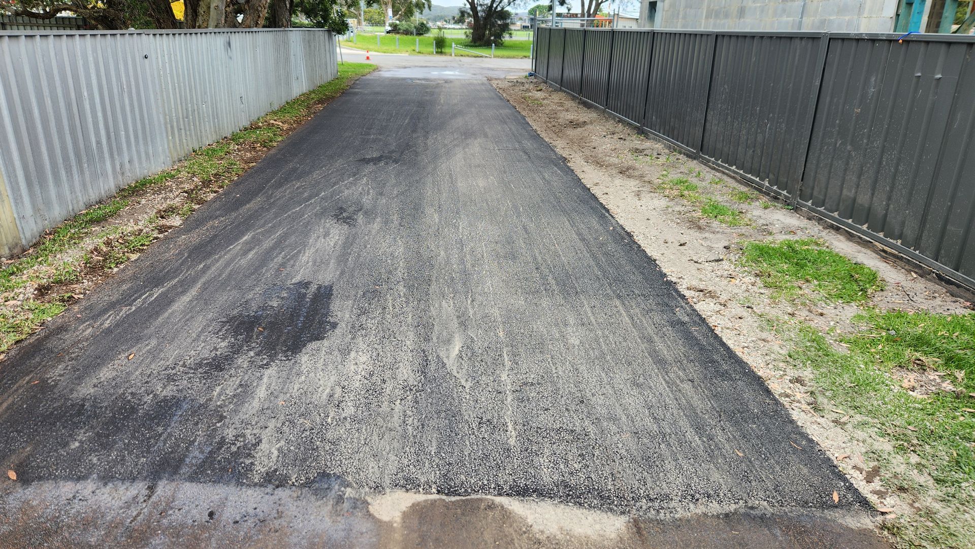Asphalt Driveway Between Fences With Grass On Either Side — TAC Asphalt Services in Warners Bay, NSW