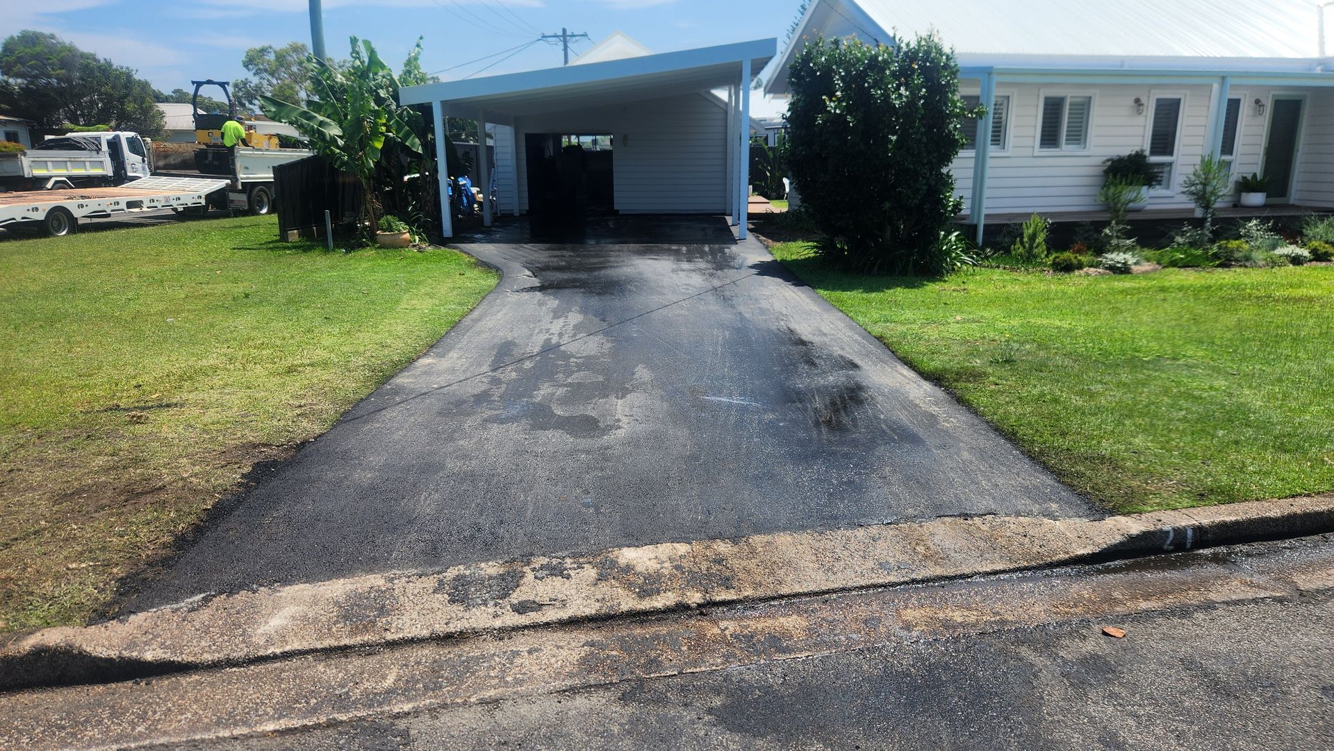 Asphalt Driveway Leading to a White House With Carport. Green Grass Surrounds — TAC Asphalt Services in Lake Macquarie, NSW