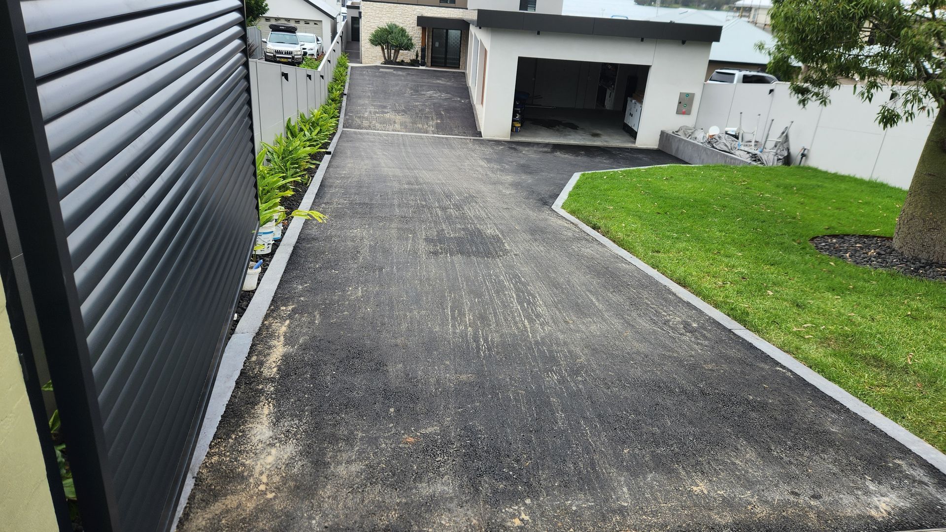 Asphalt Driveway Leading To A Garage — TAC Asphalt Services in Warners Bay, NSW