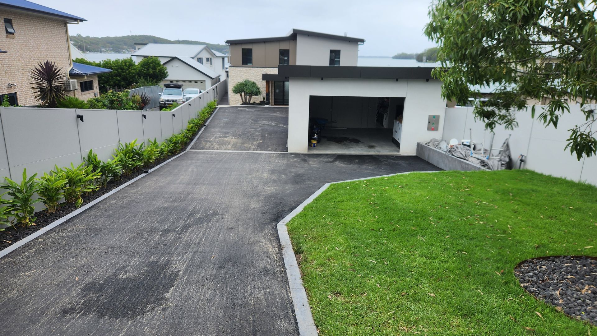 Driveway of Modern Home With Garage, Lawn, and Bordering Greenery — TAC Asphalt Services in Hunter Valley, NSW