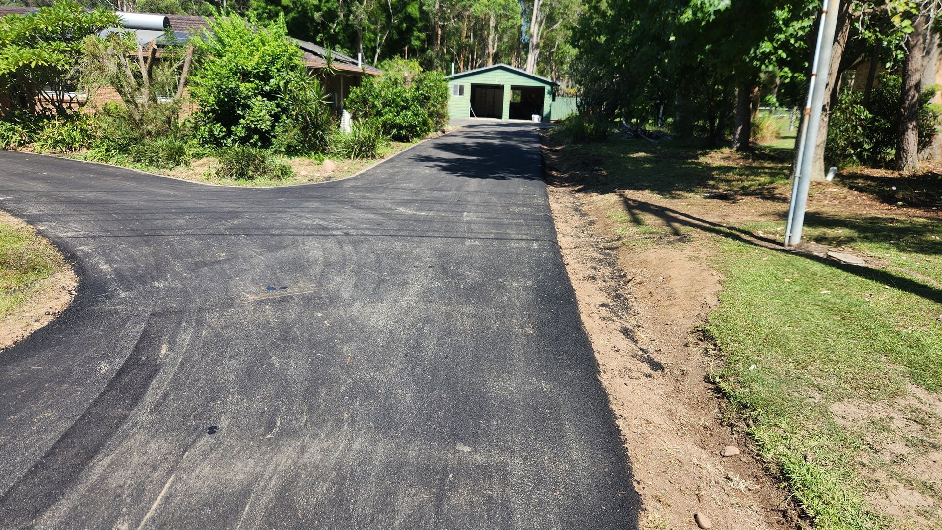 Black Asphalt Driveway Leading To A Green Shed — TAC Asphalt Services in Warners Bay, NSW