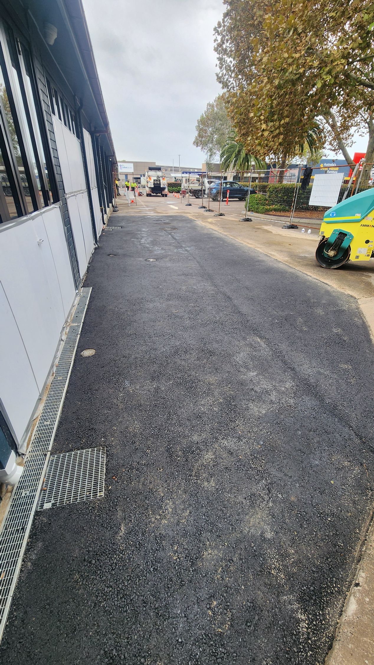 Asphalt Path Next to a Building, Leads to a Cluttered Area — TAC Asphalt Services in Raymond Terrace, NSW