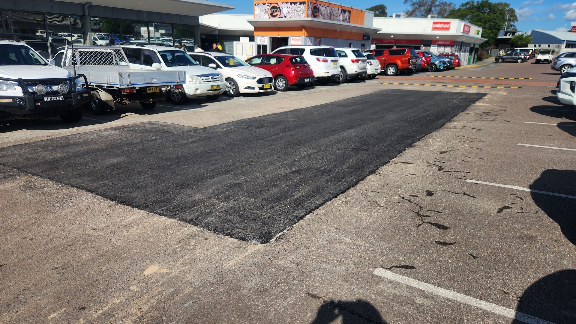 Paved Parking Area Patch In Front Of A Car Dealership — TAC Asphalt Services in Warners Bay, NSW