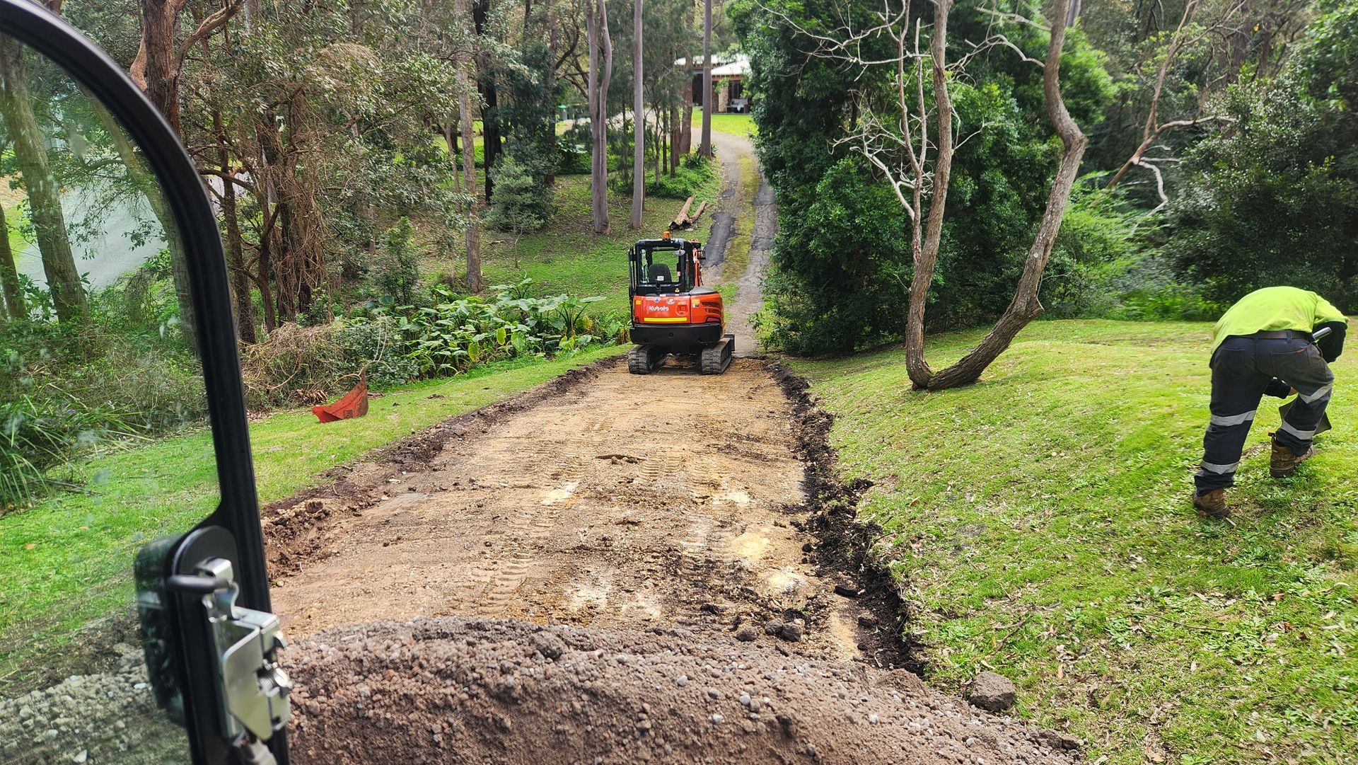 A Small Excavator On A Muddy Driveway — TAC Asphalt Services in Warners Bay, NSW