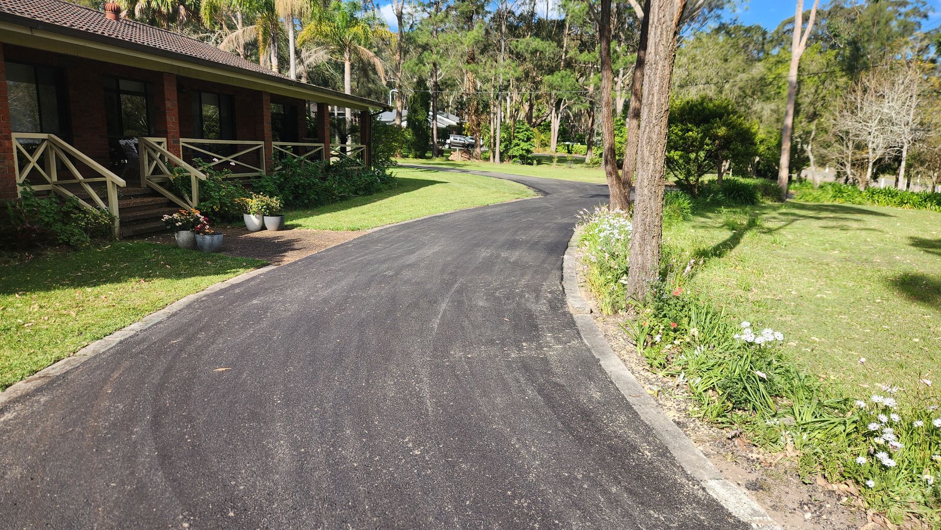 Paved Driveway Curves Toward A Rustic Home With A Porch — TAC Asphalt Services in Warners Bay, NSW