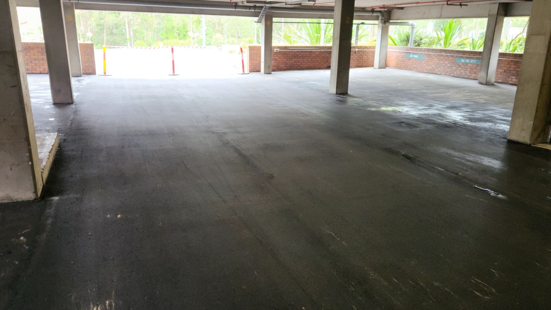 Interior of an Unfinished Building. Dark, Wet-looking Floor, Concrete Pillars — TAC Asphalt Services in Warners Bay, NSW