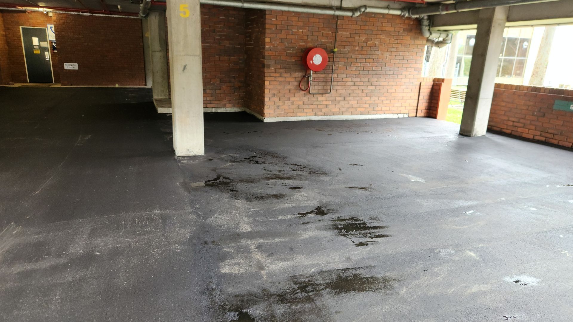 Empty, Paved Parking Area Under A Brick Building — TAC Asphalt Services in Warners Bay, NSW