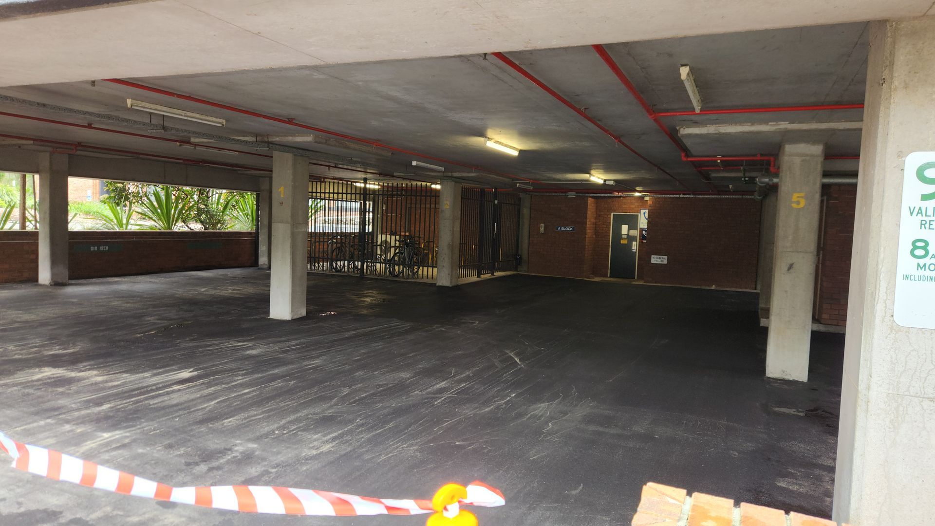 An Empty, Open-air Parking Garage With Concrete Pillars And Brick Walls — TAC Asphalt Services in Warners Bay, NSW