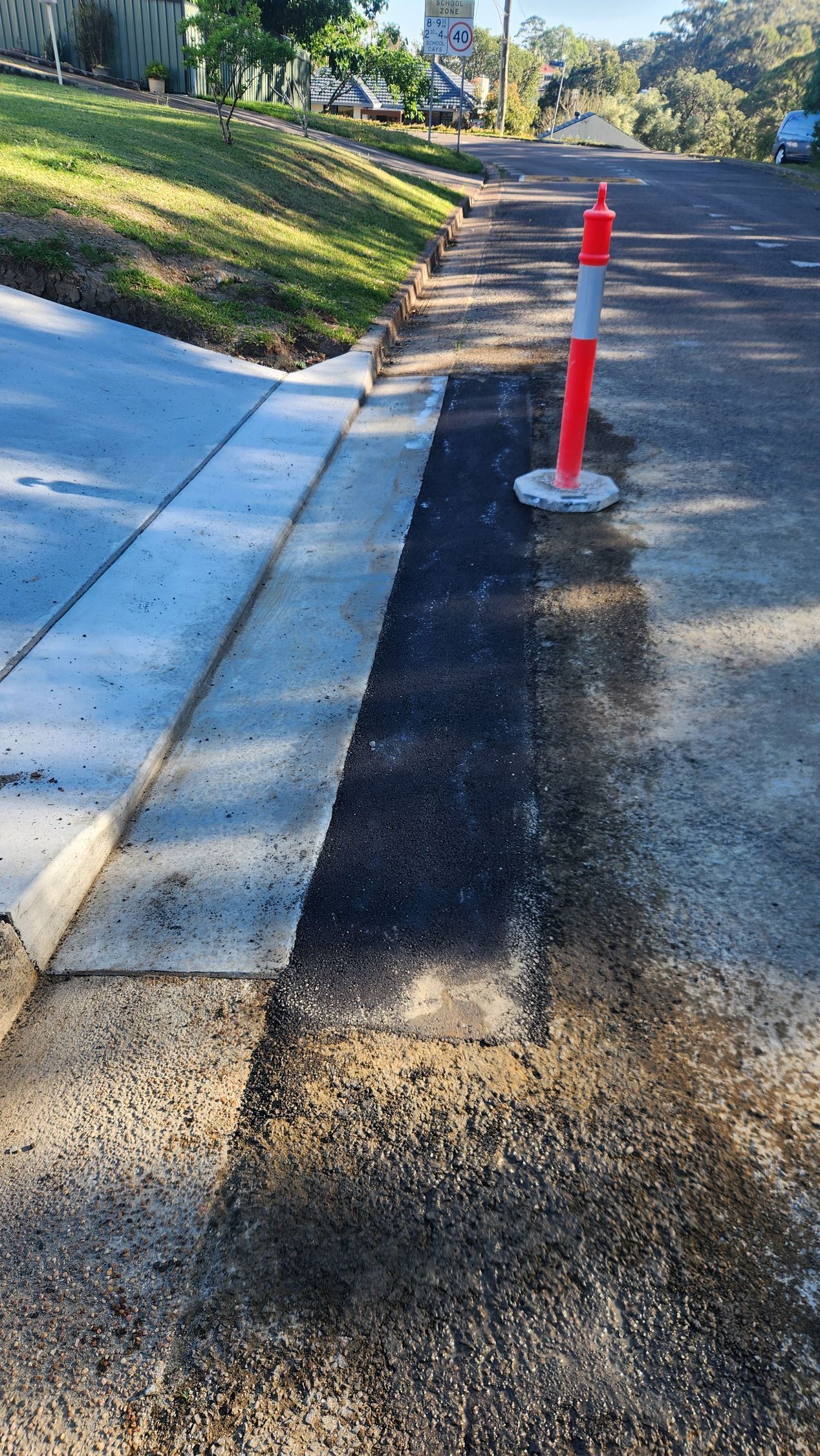 Roadside Asphalt Repair With Orange And White Cone Next To A Curb — TAC Asphalt Services in Warners Bay, NSW