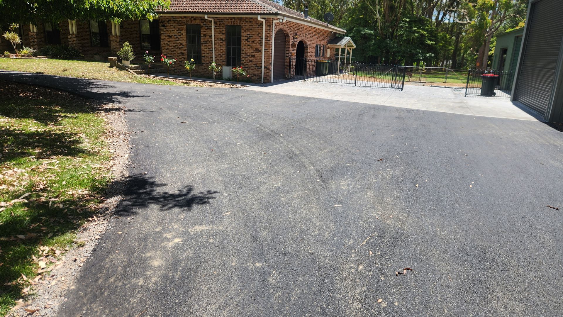 Asphalt Driveway Leads To A Brick Building — TAC Asphalt Services in Warners Bay, NSW