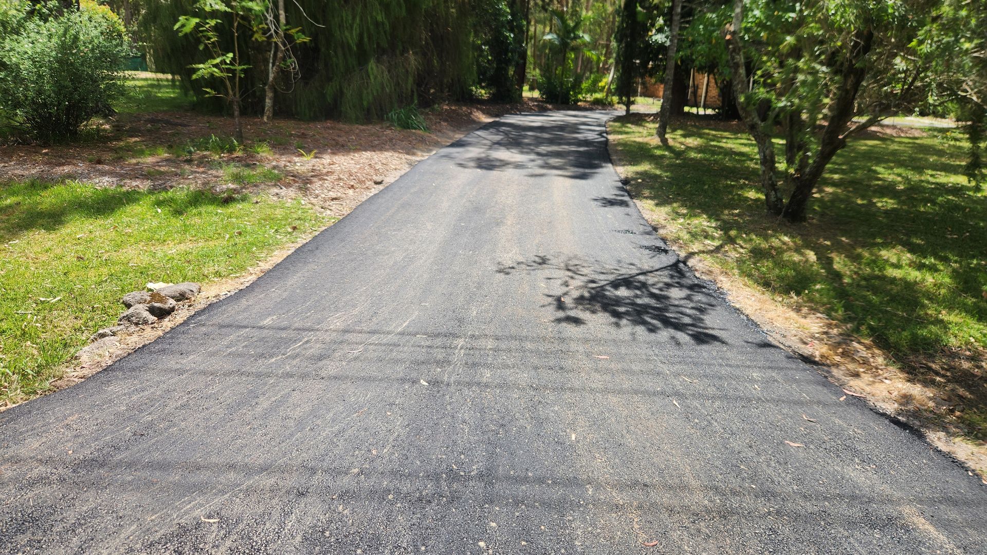 Asphalt Driveway Through A Grassy Yard — TAC Asphalt Services in Warners Bay, NSW
