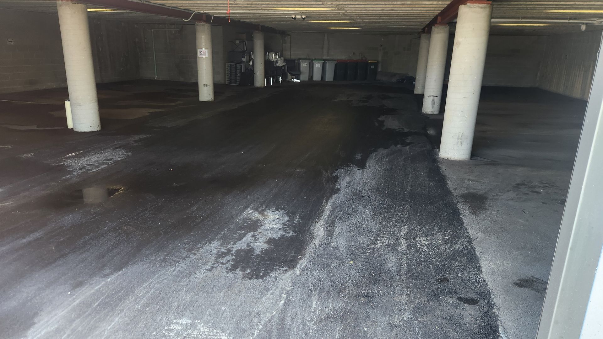 Wet Parking Garage With White Support Columns And A Person In The Distance — TAC Asphalt Services in Warners Bay, NSW