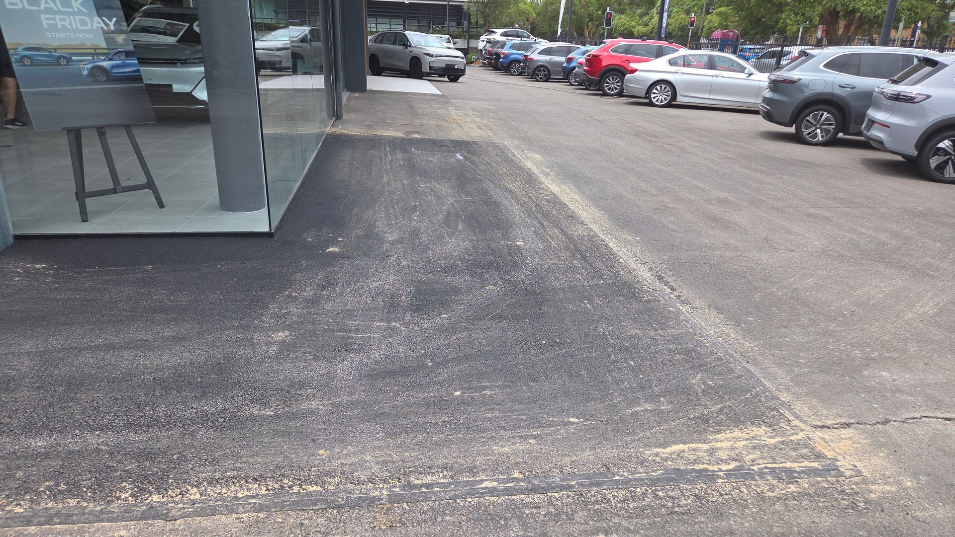 Asphalt Surface Outside A Building With Cars Parked Nearby — TAC Asphalt Services in Warners Bay, NSW