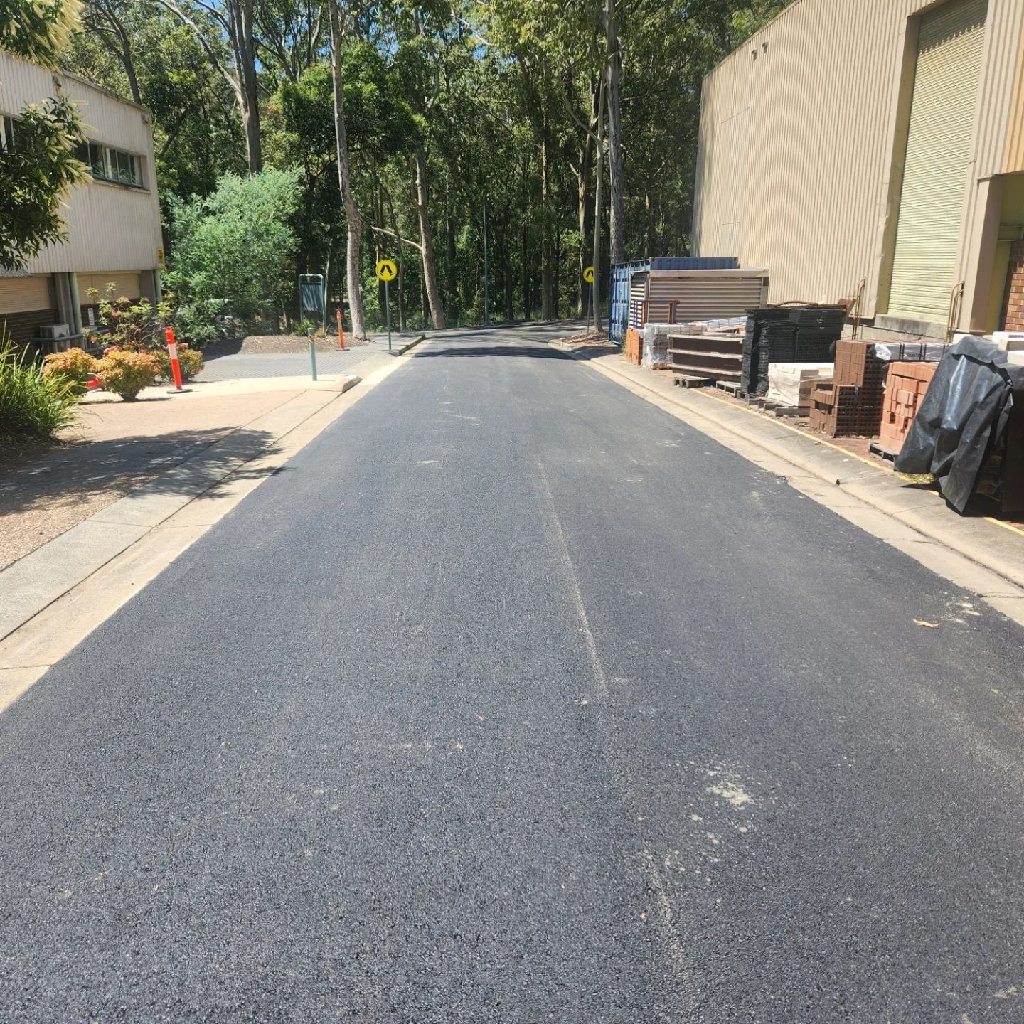 Freshly Paved Asphalt Road Bordered By Sidewalks And Buildings — TAC Asphalt Services in Warners Bay, NSW