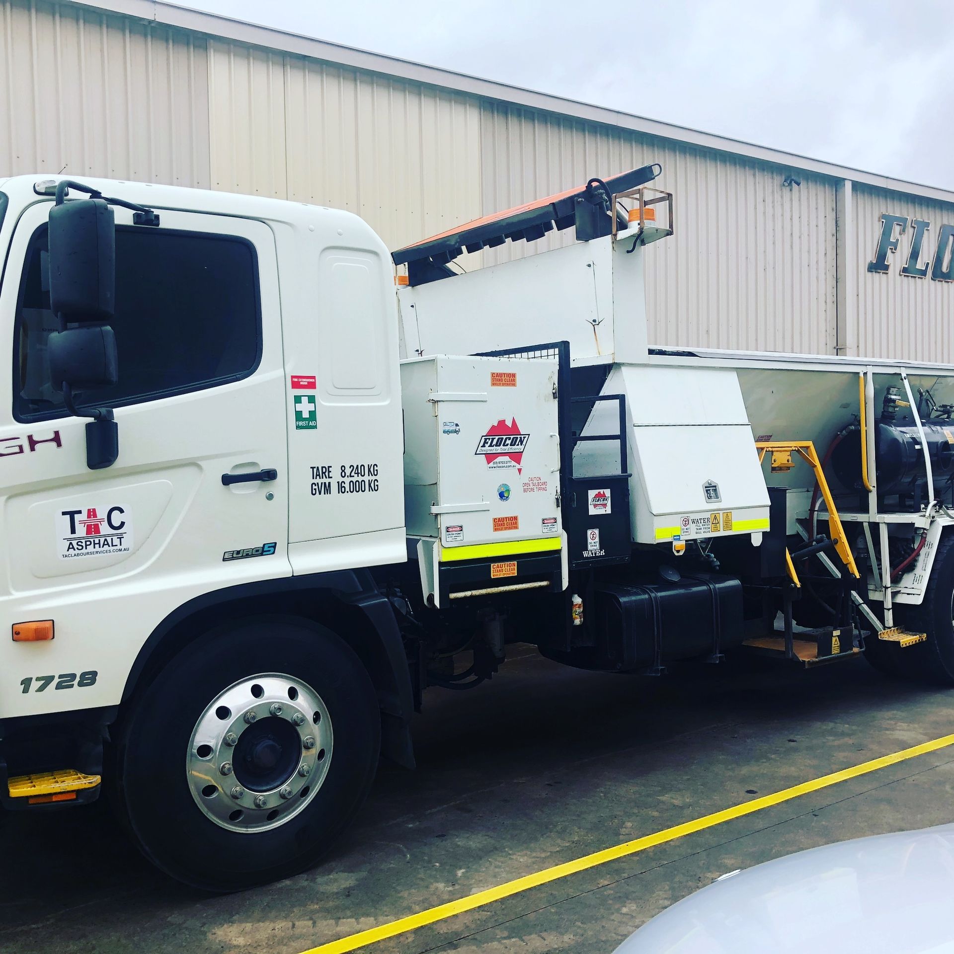 White Truck With Extended Arm, Parked In Front Of A Building — TAC Asphalt Services in Warners Bay, NSW