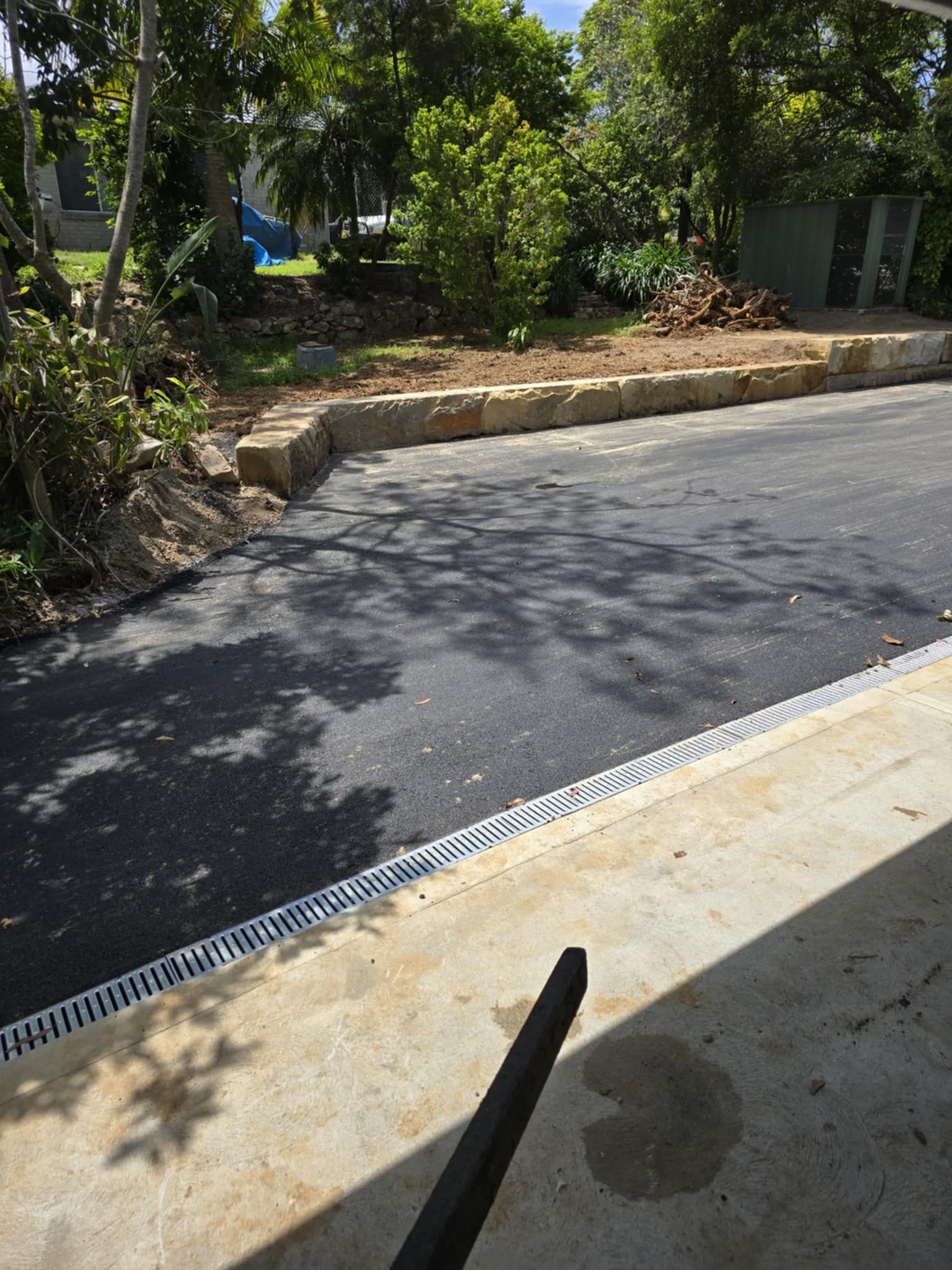 Asphalt Driveway Bordered By Stone Wall And Concrete Slab — TAC Asphalt Services in Warners Bay, NSW