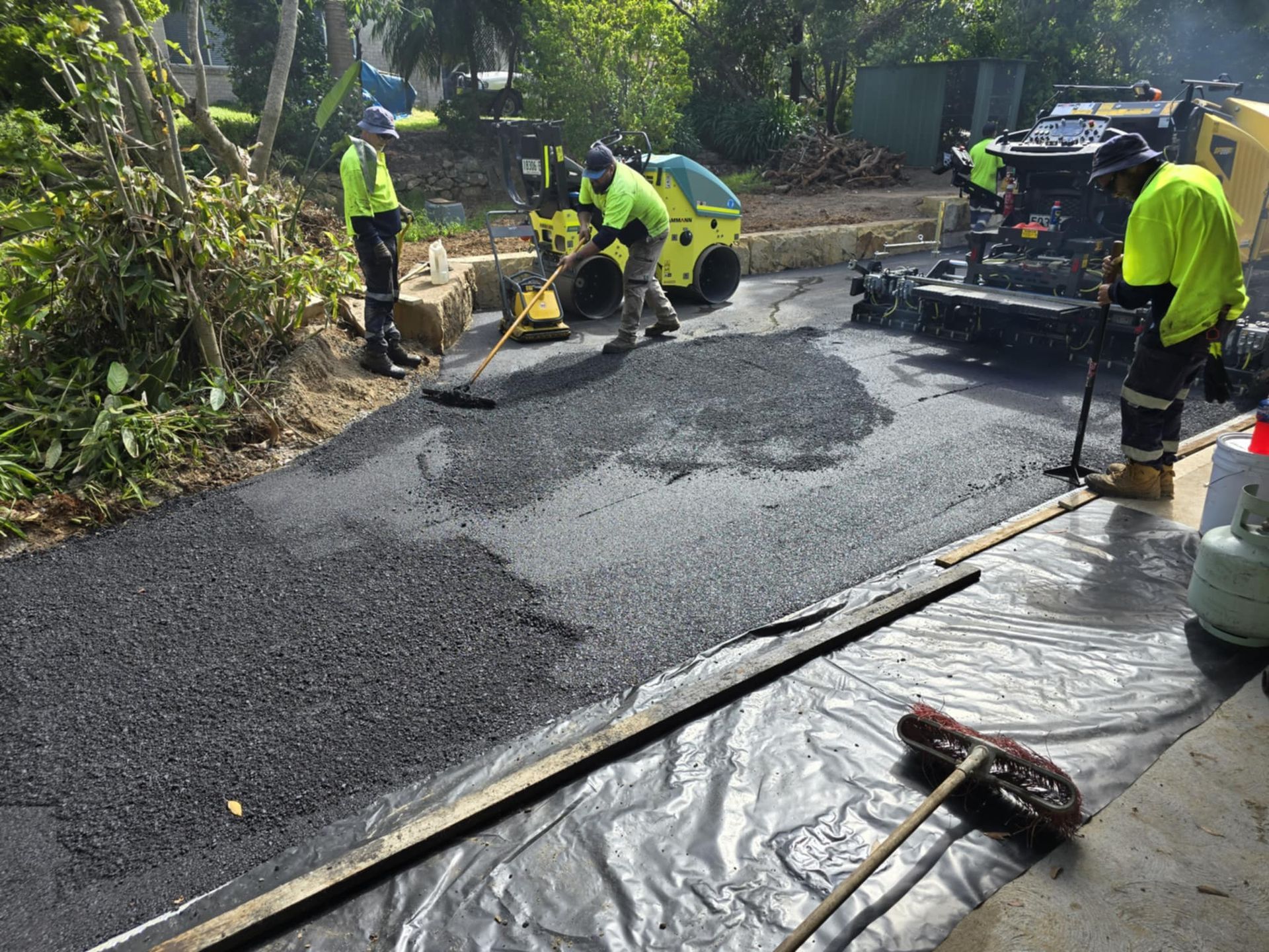 Workers in Safety Vests Spread and Compact Asphalt on a Street — TAC Asphalt Services in Warners Bay, NSW