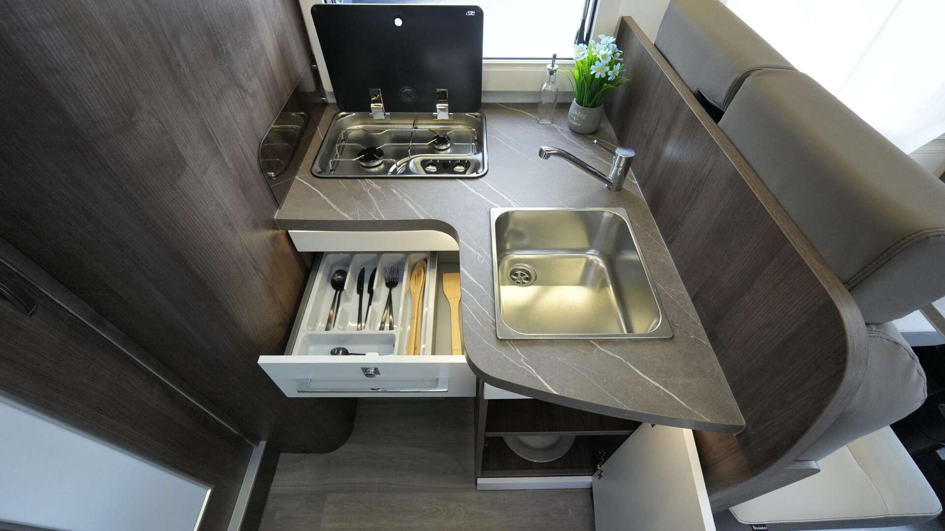 Camperkeuken met kookplaat, spoelbak en besteklade.