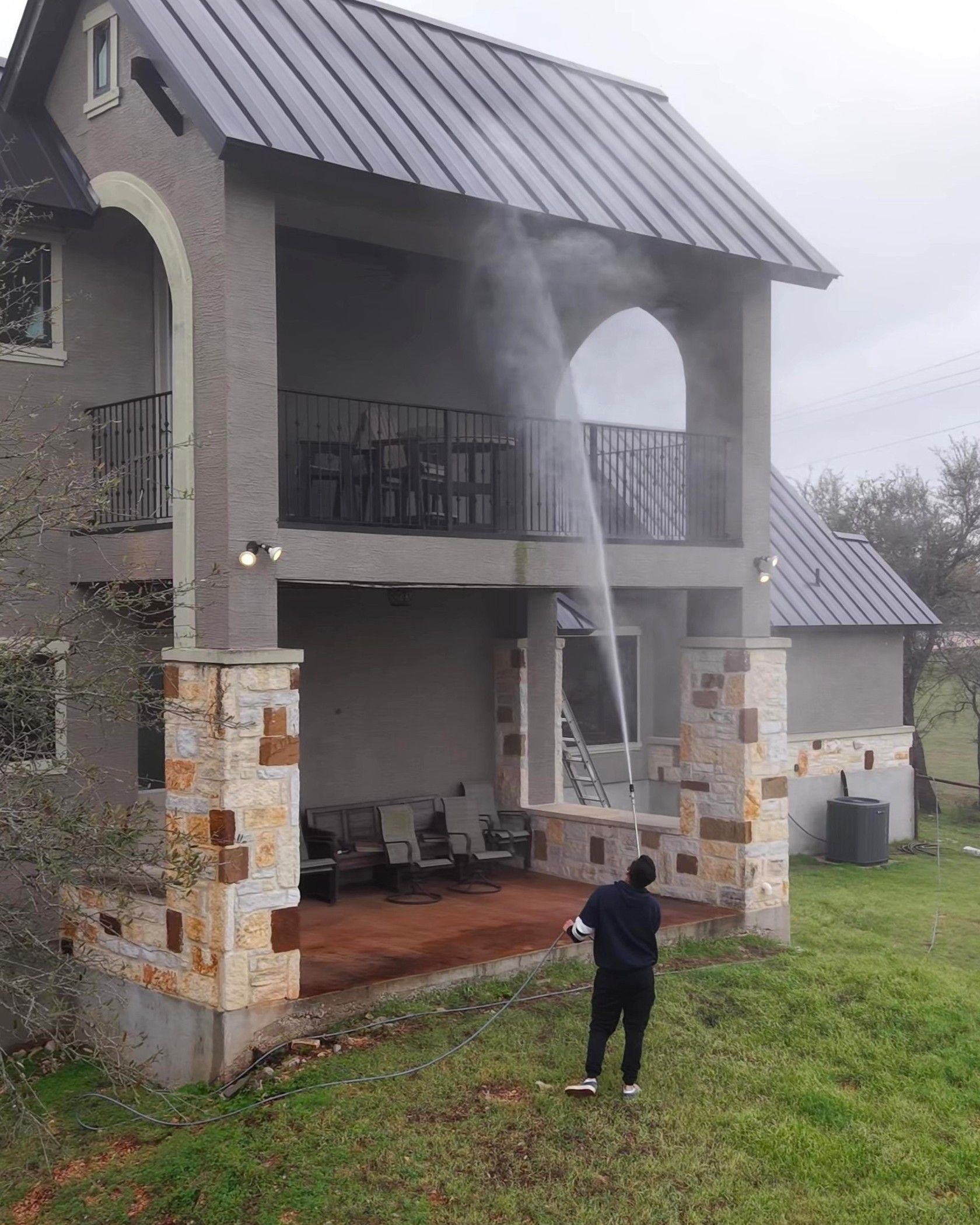 A man is spraying water on the side of a house.