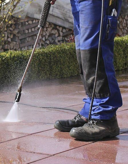 A person is using a high pressure washer to clean a tiled floor.