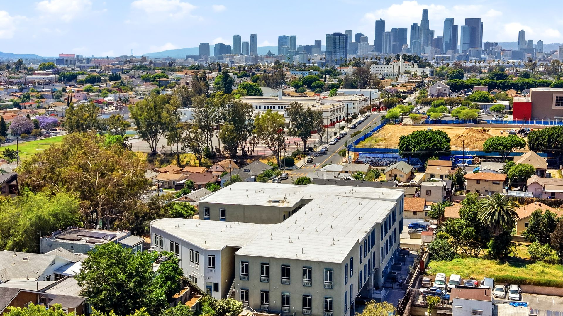 Aerial view of grey and white apartment building with Downtown Los Angeles skyline in distance