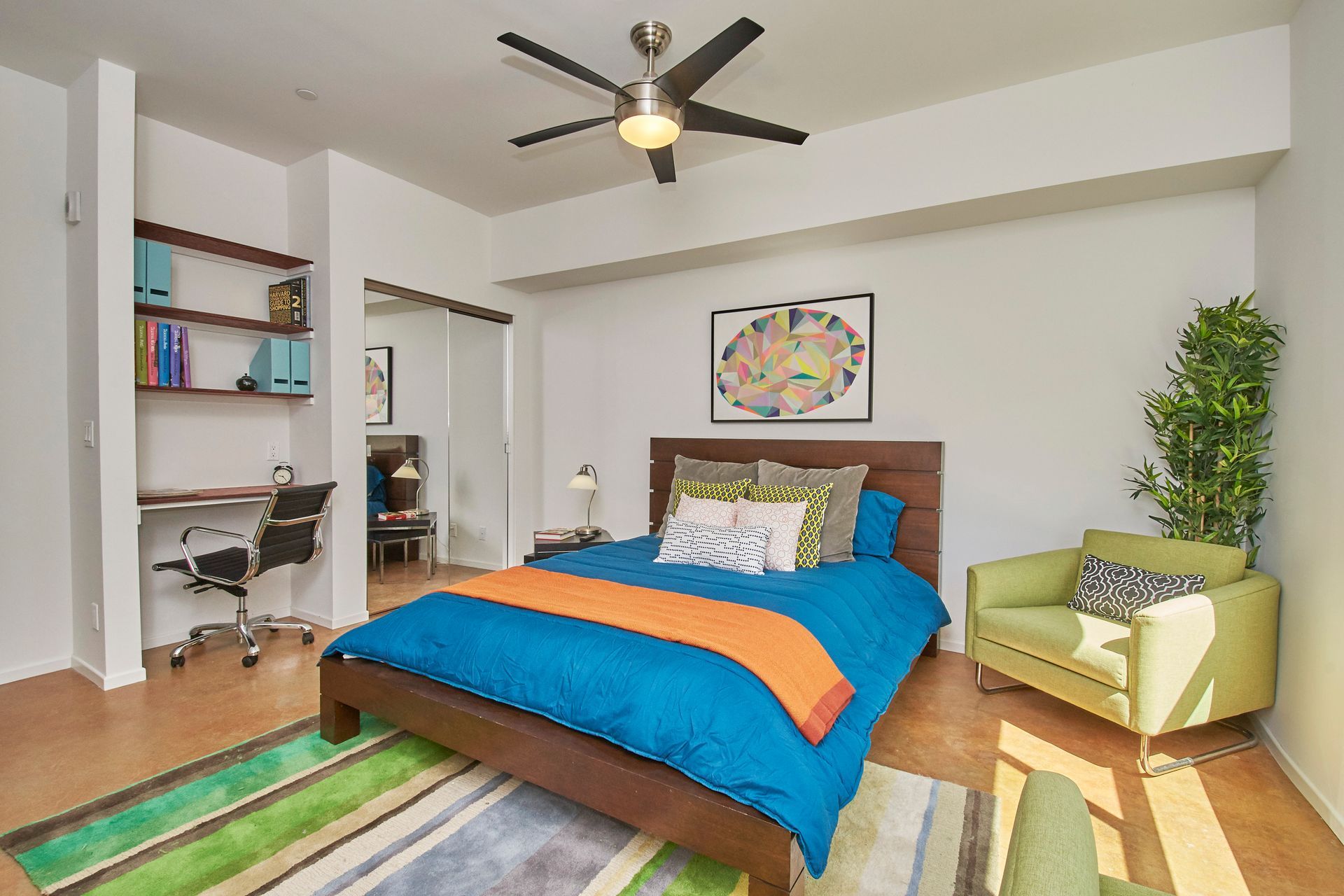 A bedroom with a bed , chair , desk and ceiling fan.