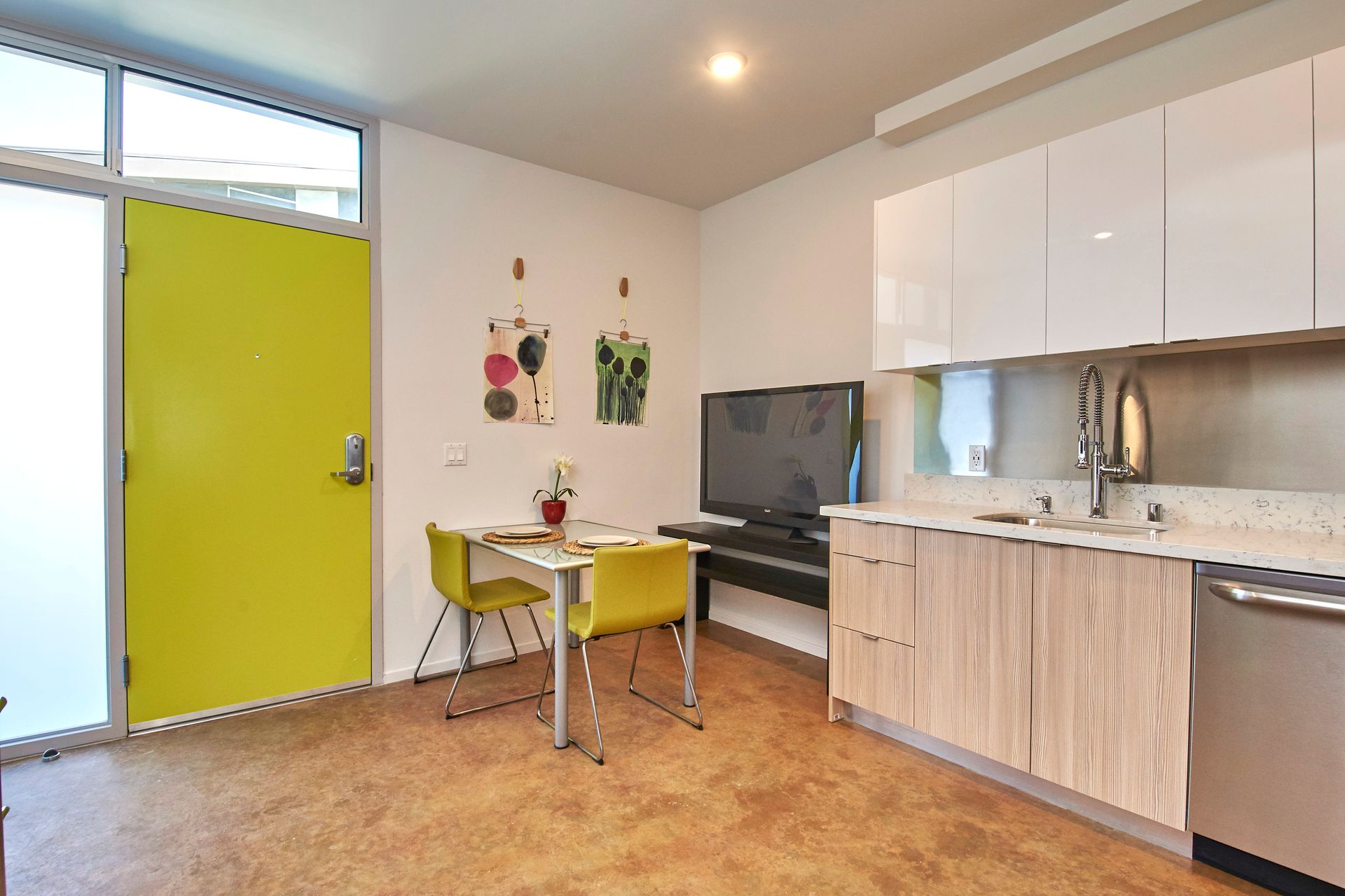 A kitchen with a yellow door and a table and chairs
