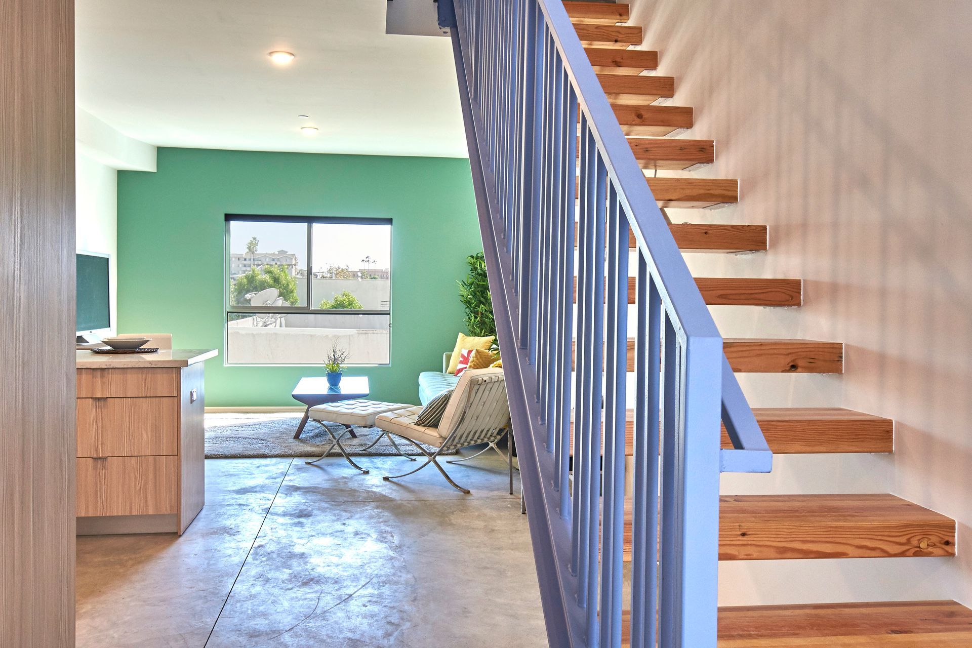 A staircase leading up to a living room with a blue railing